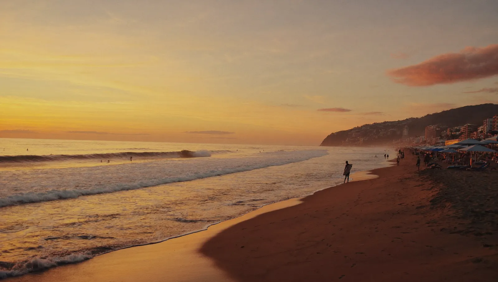 Sunset over Canggu beach in Bali with surfers and beach clubs along the shore